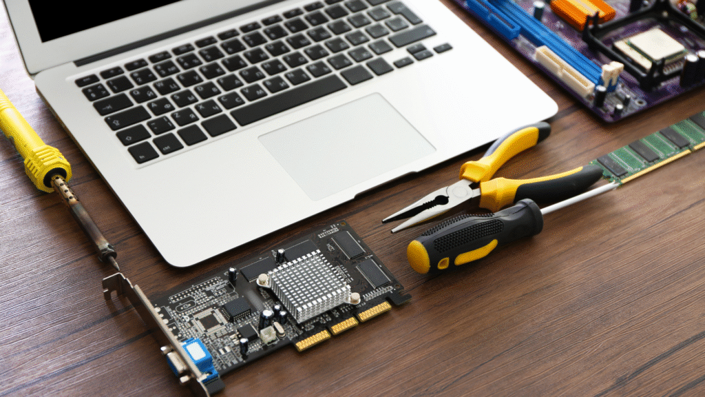 Laptop and disassembled computer hardware components with tools like a screwdriver and soldering iron, symbolizing technical maintenance and repair skills.